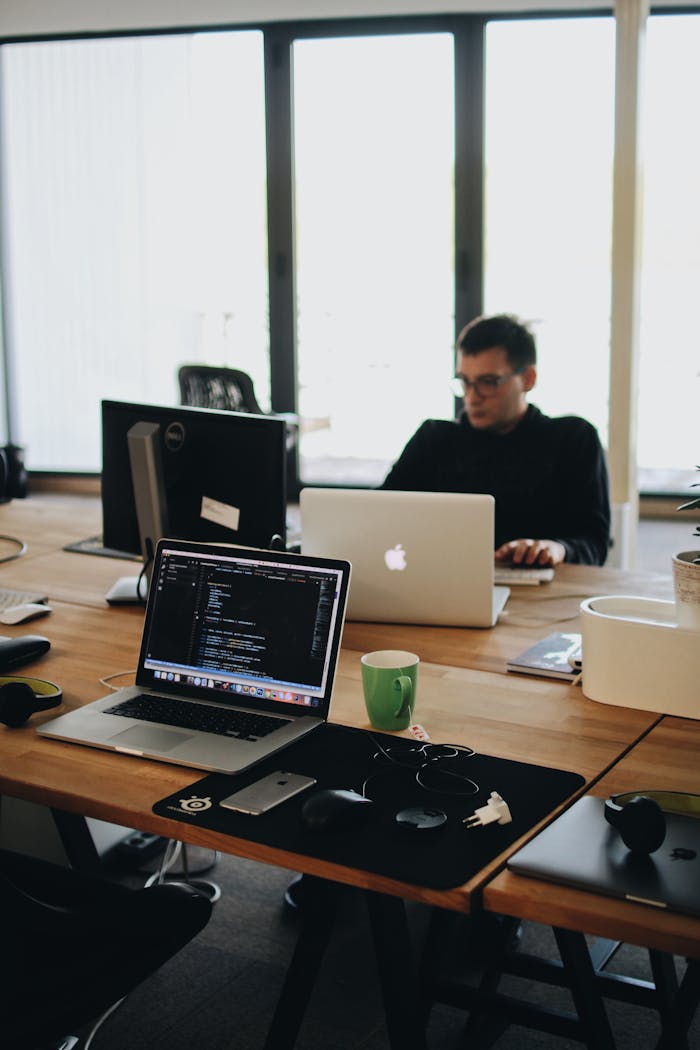 why-choose-us A web developer working on code in a modern office setting with multiple devices.